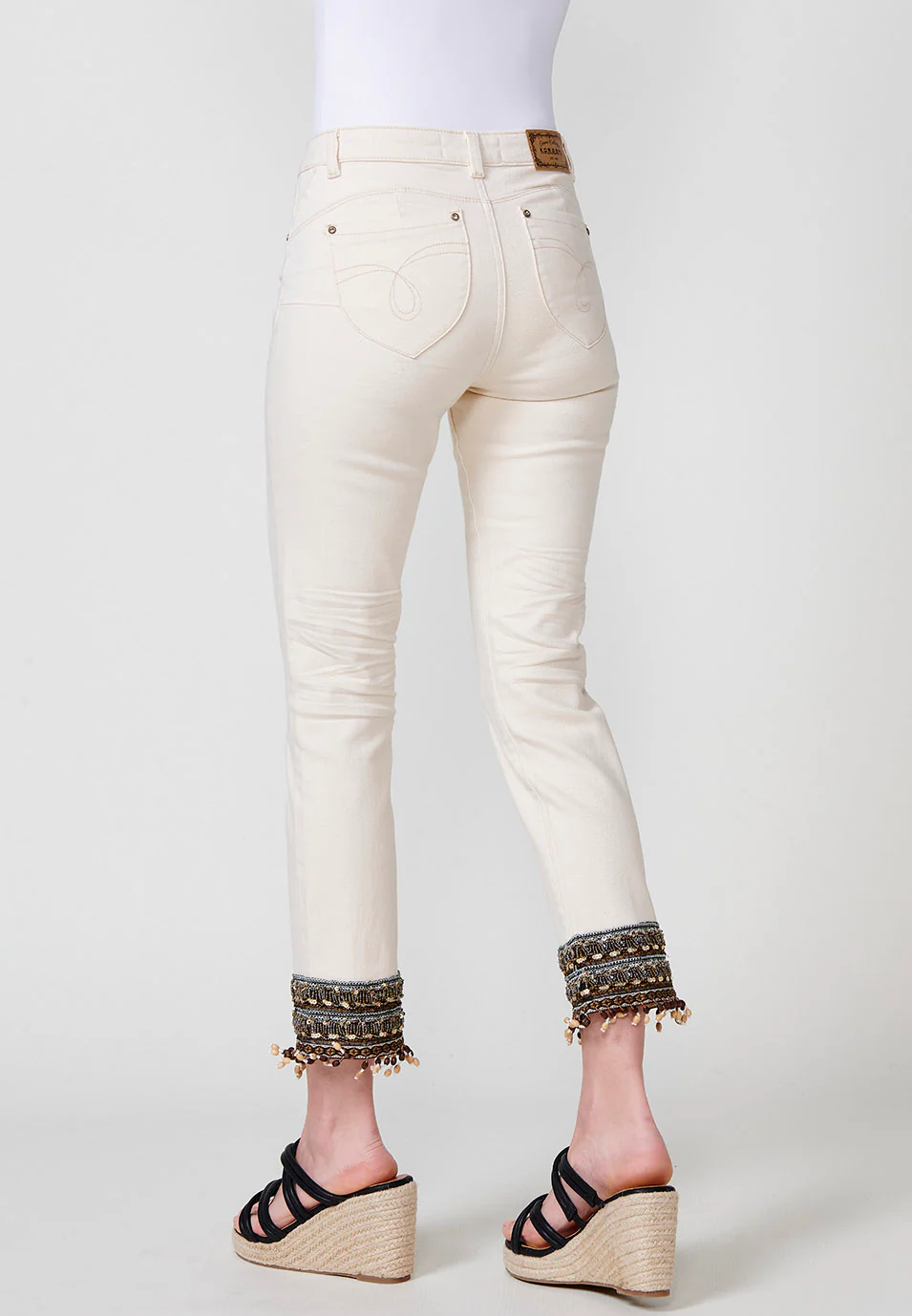 Pantalón jeans elástico cropped push up slim de tiro medio y cinco bolsillos con cierre con cremallera y botón metálico y detalle bordado con lentejuelas y flecos con abalorios y bolas de madera en el bajo para mujer - Image 7